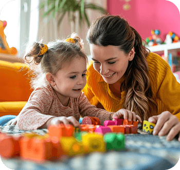 Teacher and child smiling while building with colorful blocks